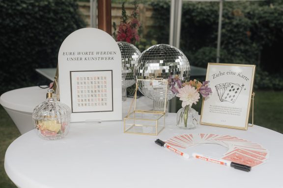 Tisch mit Dekorationen, Signaturen, Blumen und einem Rahmen mit einer Nachricht.