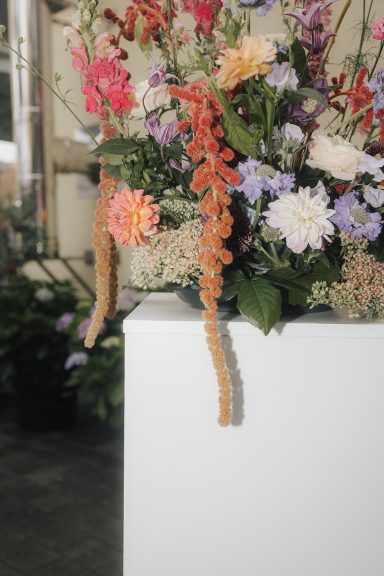 Bunte Blumenarrangements mit verschiedenen Pflanzen und Blüten in einem modernen Blumenbehälter.