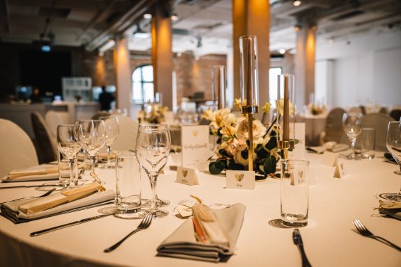 Eleganter Tisch mit gedecktem Geschirr, Kerzenhaltern und Blumendekoration.